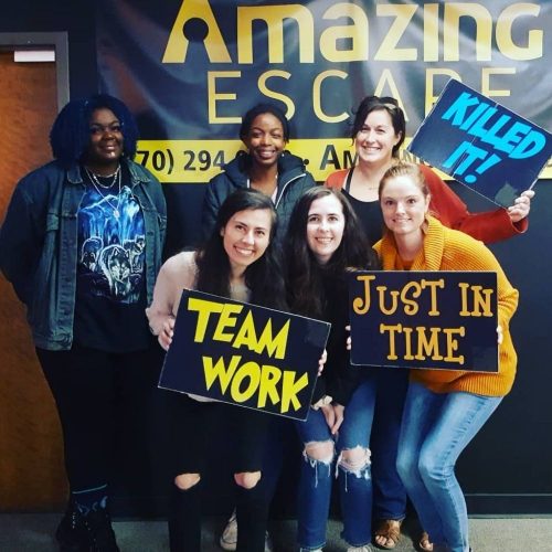 group of women that escaped the room with team work sign in their hands